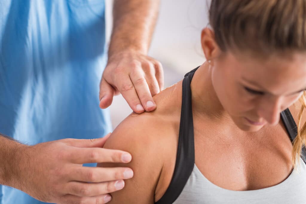 Physiotherapeut tastet Nacken- und Schultermuskulatur nach Schleudertrauma ab